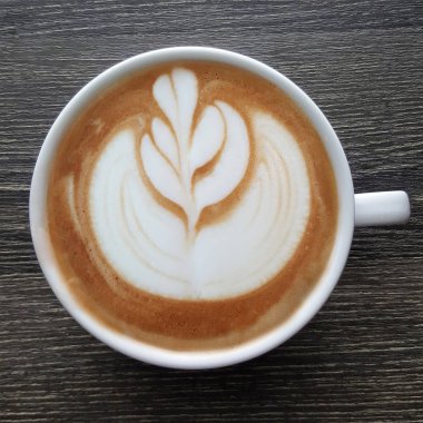 Bir fincan kahve latte sanat üstten görünüm ahşap arka plan üzerinde.