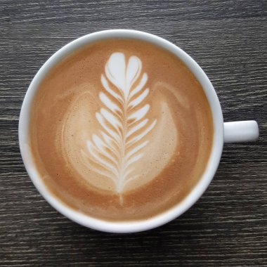 Bir fincan kahve latte sanat üstten görünüm ahşap arka plan üzerinde.