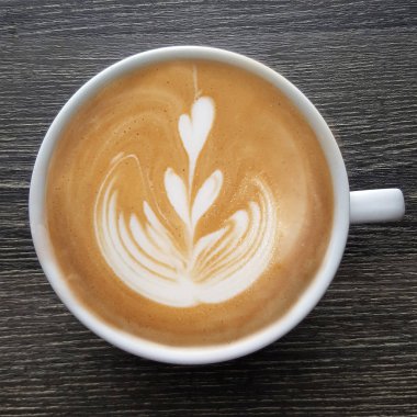 Bir fincan kahve latte sanat üstten görünüm ahşap arka plan üzerinde.