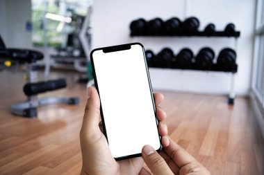 Genç adam Hand spor salonunda spor salonunda spor salonu konsepti için akıllı telefon tutuyor.