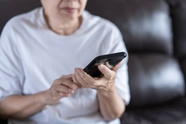 Yaşlı kadın evde telefonunu kullanarak