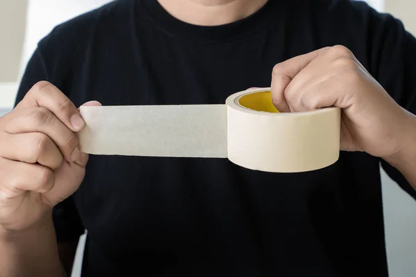 Close up of a man packaging tape roll adhesive tap