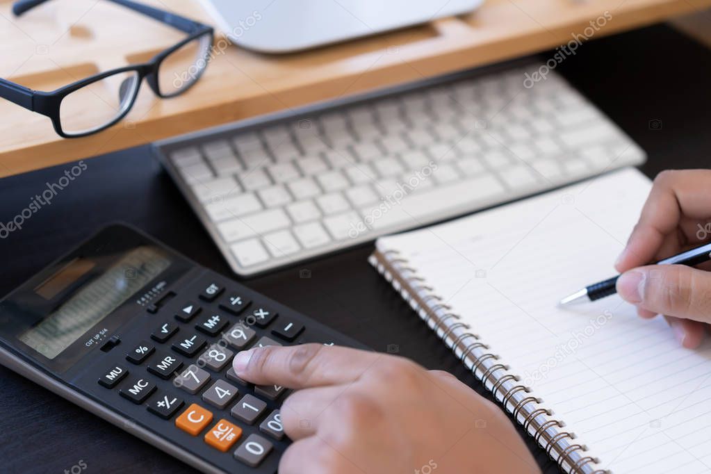 man use calculator  make note with calculate about cost  in office Close up