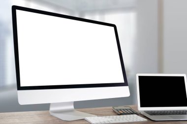 İşadamı el bilgisayarı üzerinde çalışıyor ahşap masaüstü bilgisayarı ve boş ekranı var..