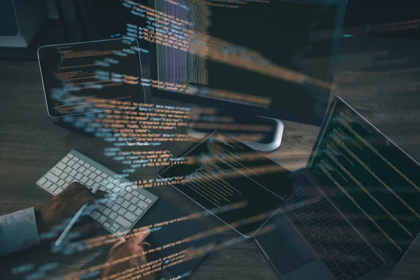 Kodlama ve yazılım geliştirme kavramı, programcı dizüstü bilgisayar, tablet ve ekranda parlayan kod satırlarını göstererek klavyede yazarken.