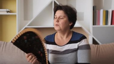 Kadınlar yüksek sıcaklıktan rahatsız olan sıcak hava dalgası hayranlarını evde otururken hissederler. Klimasız yaz havası sorunu
