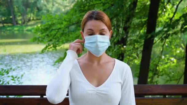 A fiatal nő leveszi az orvosi maszkot - kültéri. Egészségügyi ellátás és orvosi koncepció. — Stock videók