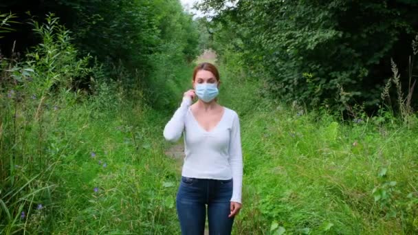 Ung kvinna tar av sig medicinsk mask utomhus. Hälso- och sjukvård. — Stockvideo