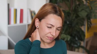 Başı ağrıyor ve sırtı ve boynu ağrıyor diye boynunu tutan genç bayanı yakından çek. Portre. Kapalı