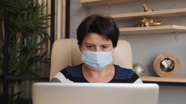 Coronavirus检疫办公室里的女人带着科罗那病毒的面具商界女性戴口罩来保护和照顾自己的健康。在家和电脑一起工作。在家工作. — 图库视频影像