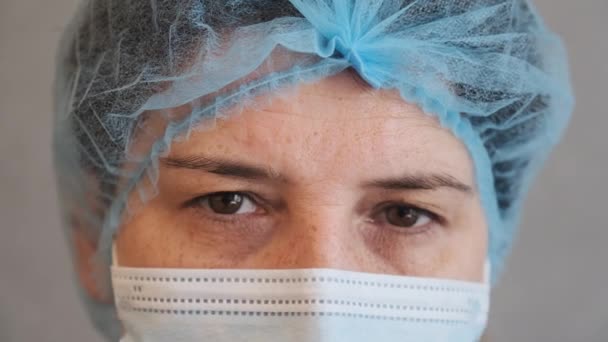 Medico triste e stanco apre gli occhi e guardando dritto alla macchina fotografica. medico roba ritratto primo piano. Donna in maschera protettiva — Video Stock