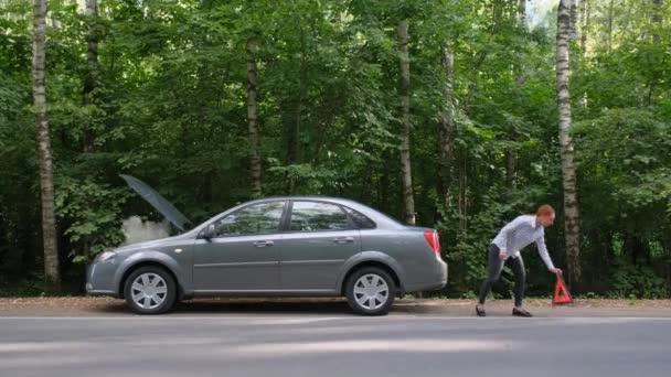 Femme installant signe triangle rouge dans la forêt. Malheur sur la route de campagne, conductrice avec automobile cassée, accident de voiture. — Video