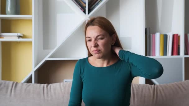 Gros plan de la jeune femme tenant son cou derrière elle alors qu'elle a mal à la tête et ressent des douleurs au cou et au dos. Portrait. Intérieur — Video