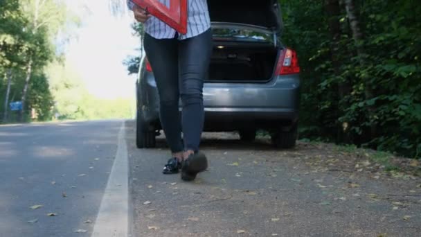 Γυναίκα εγκαθιστά κόκκινο τρίγωνο σημάδι στον προαστιακό δρόμο. Ατυχίες στην ύπαιθρο, γυναίκα οδηγός με σπασμένο αυτοκίνητο, αυτοκινητιστικό ατύχημα. — Αρχείο Βίντεο