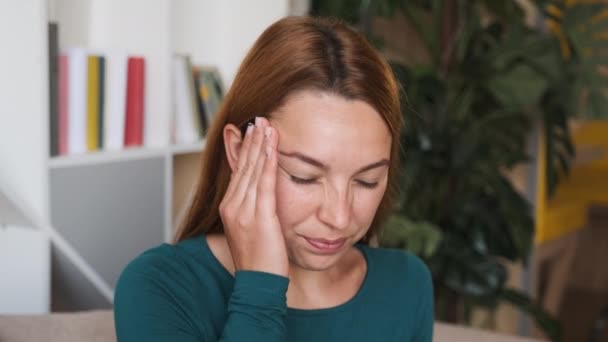 Mladá žena masírující si čelo ze strany, protože ji bolí hlava. — Stock video