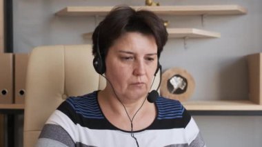 Konferans çağrısı ile iletişim kuran kulaklık takan bir kadın evdeki bilgisayara, görüntülü sohbet iş görüşmesine ya da internet öğretmenliği konseptine sahip uzak dil kursuna bakıyor..