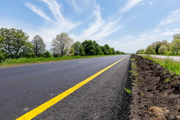 Yeni boş yol tarafında yeşil ağaçlar ile