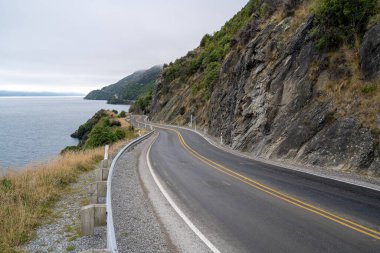 Wakatipu Gölü boyunca bulutlu gökyüzü olan güzel bir yol, Queenstown, Yeni Zelanda.