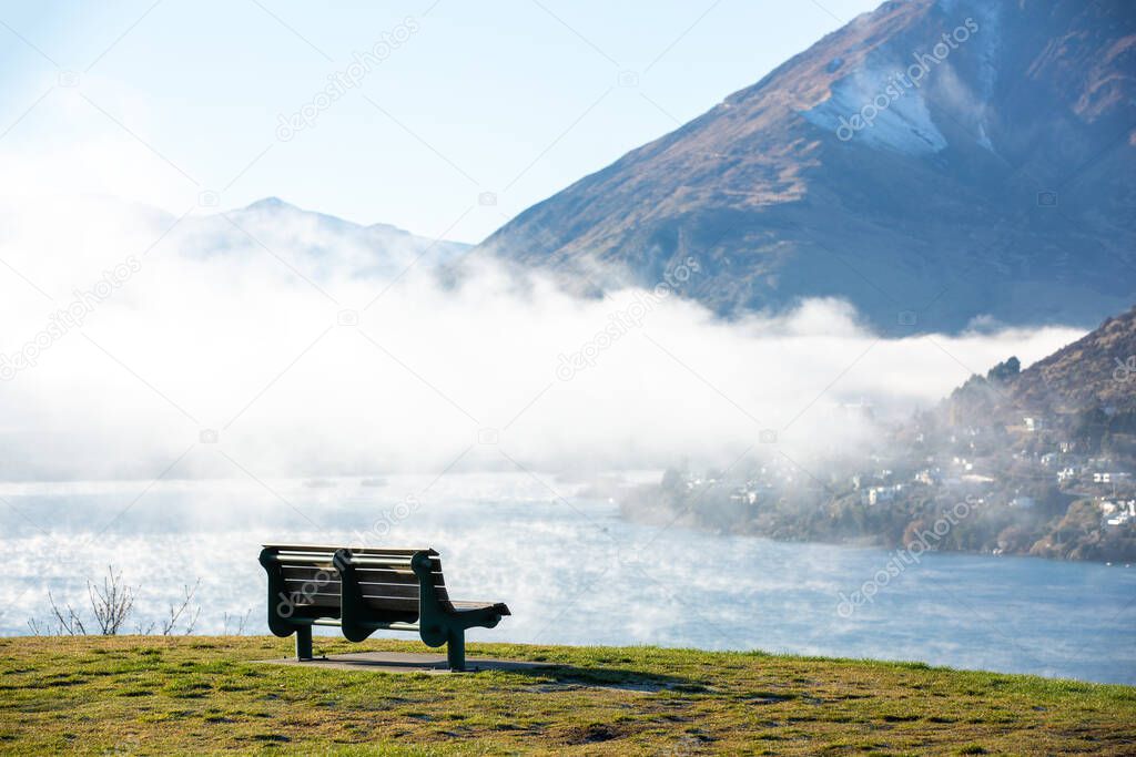 Misty landscape with fir forest of pine trees and wooden bench in New Zealand.
