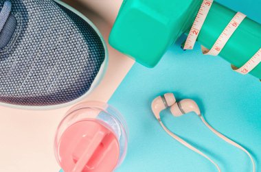 Yeşil dumbbell ve mavi arka plan üzerinde spor ayakkabısı. Egzersiz kavramı.