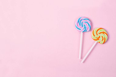 Metin veya ileti için boş alan ile pembe arka plan üzerinde iki lolipop. tatlı şeker kavramı