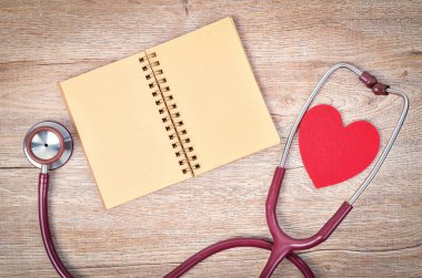 Açık boş defter ile metin veya mesaj ahşap arka plan üzerinde stetoskop tıbbi ve kırmızı kalp.
