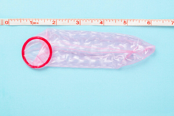 Red unpack condom compare measuring tape on blue background with copy space for your text or message.