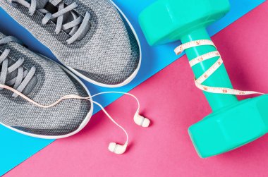 Yeşil dumbbell ve pembe bir arka plan üzerinde spor ayakkabısı. Egzersiz kavramı.