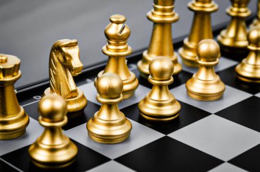 Siyah ve beyaz satranç tahtasının altın satranç taşları.