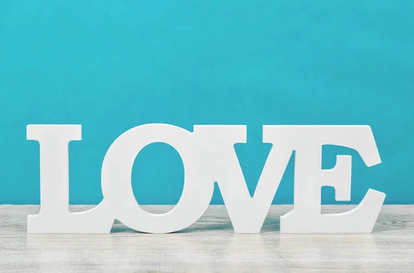 White wooden word love on blue background.