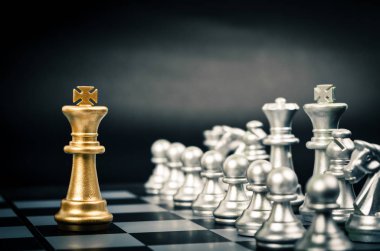 Satranç oyununda altın kral siyah zemin üzerinde başka bir gümüş takım ile karşı karşıya (Şirket stratejisi, iş zaferi veya karar kavramı)