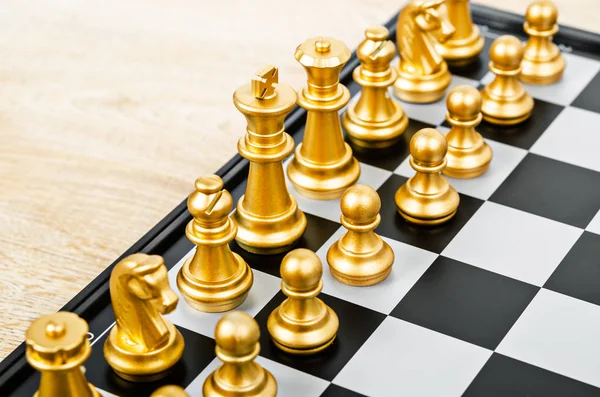 chess game face with the another gold team on wooden background (Concept for company strategy, business victory or decision)