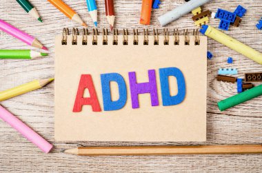 Dikkat Eksikliği Hiperaktivite Bozukluğu veya ahşap arka planda oyuncaklara karşı tahta kalemle ADHD konsepti.