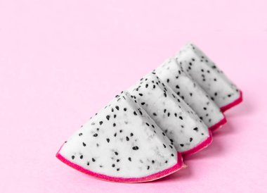 Pembe arka planda taze ejderha meyvesi dilimi.