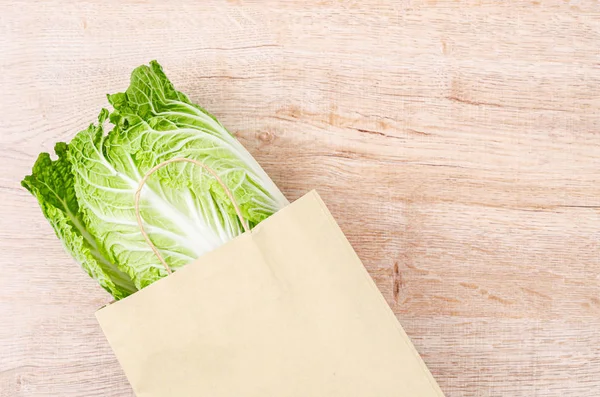 Fresh chinese cabbage in bag paper on wooden background.