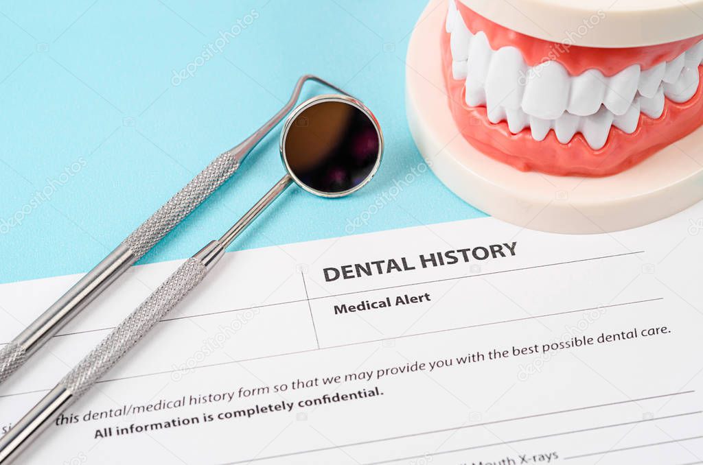 Formulario de historia dental con modelo de dientes e instrumentos