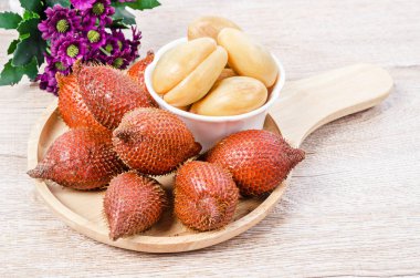 Aşağıdaki masada, ahşap çanak içinde, avuç içi, feragat veya yılan meyvesi.