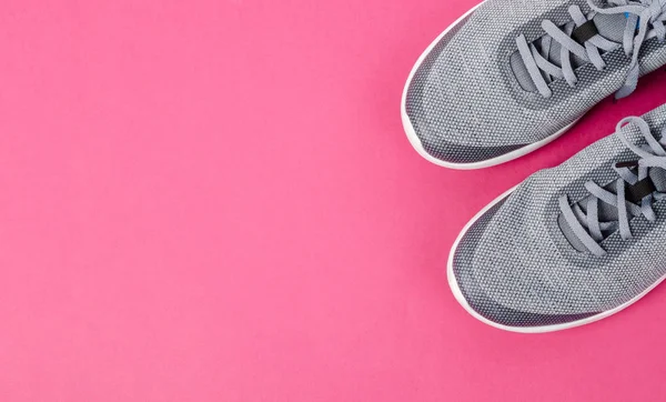 Pembe arka planda gri spor ayakkabılar. Düz konum, üst görünüm minimum arkaplan. Moda blogu veya dergi konsepti.