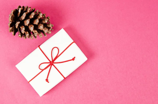 Witte geschenk doos en Pine Cornes op roze achtergrond. — Stockfoto