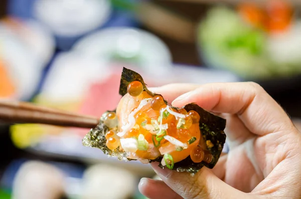 Hand hält Lachs-Sashimi mit getrockneten Algen. — Stockfoto