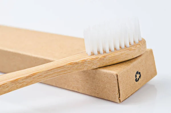 Bamboo toothbrushes on brown paper box with recycle sign. — Stock Photo, Image