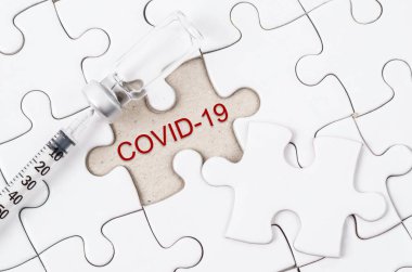 Yapboz üzerinde COVID-19 metni olan aşı ve şırınga enjeksiyonu. Korona virüsü enfeksiyonunu önleme, aşılama ve tedavi. Tıp bulaşıcı kavramı.