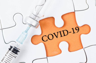 Yapboz üzerinde COVID-19 metni olan aşı ve şırınga enjeksiyonu. Korona virüsü enfeksiyonunu önleme, aşılama ve tedavi. Tıp bulaşıcı kavramı.