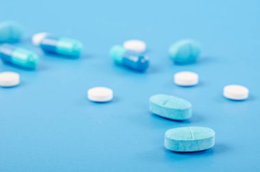 Mavi arka planda çeşitli ilaç hapları, haplar ve kapsüller..