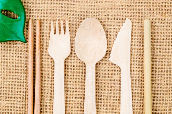 Arka planında yeşil yaprak olan ahşap mutfak aletleri. Yeşil ürün çevre dostu konsept.