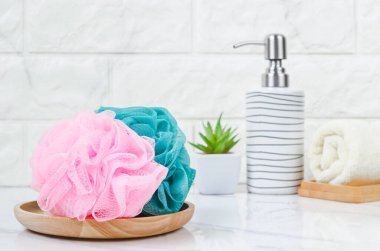 Parlak bir banyo arka planında duş süngeri ve şampuan şişesi..