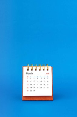 Mart 2026 mavi arkaplanda beyaz masa takvimi.