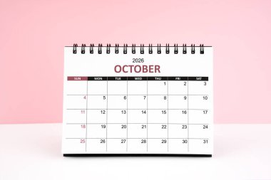 Ekim 2026 Masa takvimi pembe arka planlı beyaz masada.