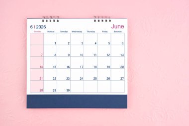 Pembe arkaplandaki 2026 Haziran masa takviminin tam üstünde.