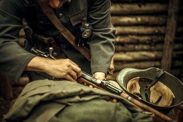 A soldier loads a cartridge in a rifle in a trench